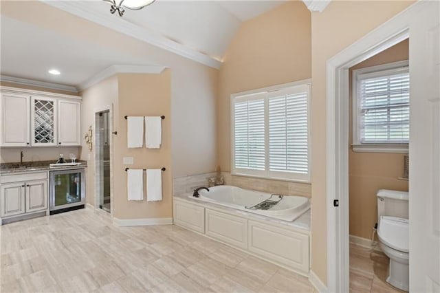 bathroom featuring toilet, vanity, vaulted ceiling, a bath, and crown molding