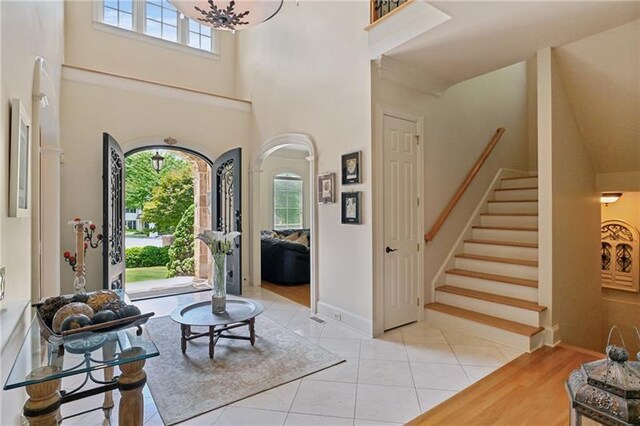 tiled foyer entrance with a towering ceiling and a chandelier