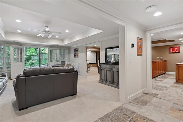 living room featuring light carpet, ceiling fan, crown molding, and a tray ceiling