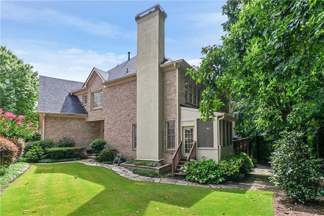 rear view of house with a yard and a sunroom