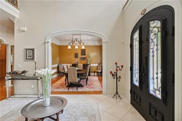 tiled foyer featuring crown molding, french doors, and decorative columns