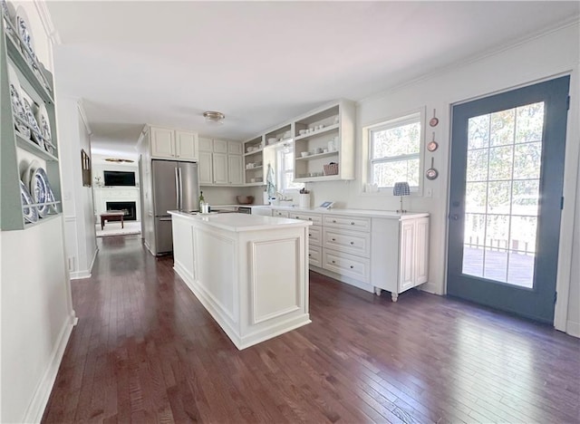 kitchen featuring open shelves, dark wood finished floors, light countertops, and freestanding refrigerator