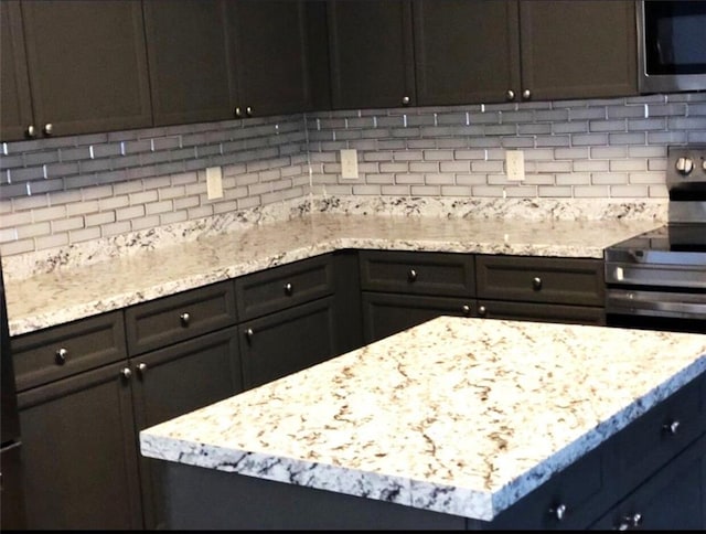 6265 Lake Windsor Pkwy, Buford, GA 30518 - kitchen with appliances with stainless steel finishes, tasteful backsplash, light stone countertops, and a kitchen island