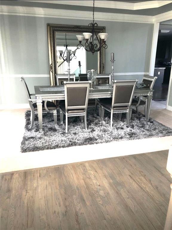 6265 Lake Windsor Pkwy, Buford, GA 30518 - dining space with ornamental molding, wood finished floors, and a chandelier