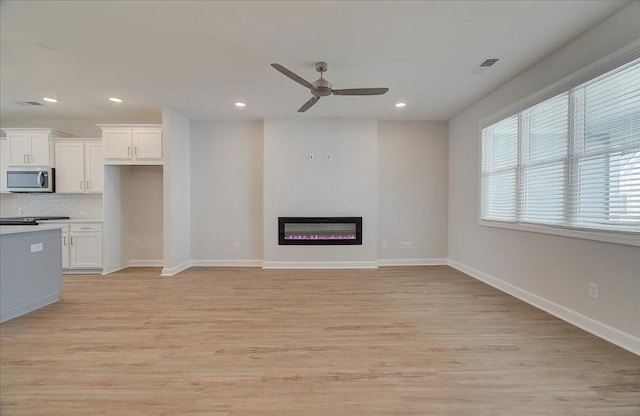 3338 Cranston Ln, Kennesaw, GA 30144 - unfurnished living room featuring a ceiling fan, light wood-style flooring, recessed lighting, a glass covered fireplace, and baseboards