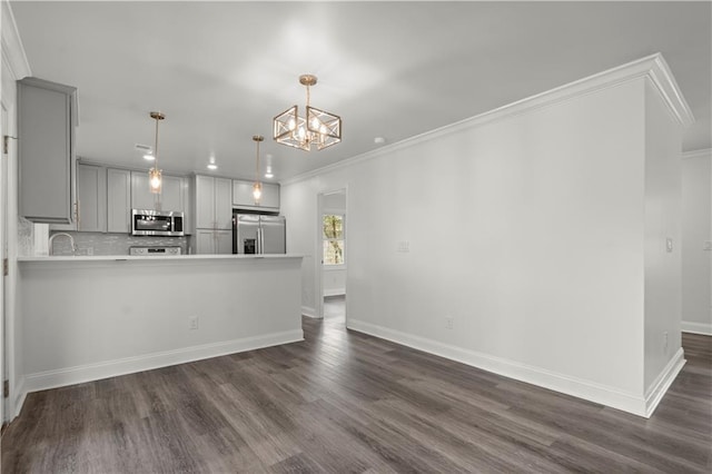 kitchen featuring ornamental molding, dark wood finished floors, a notable chandelier, gray cabinetry, and stainless steel appliances