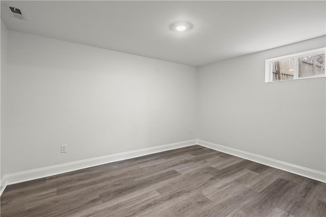 unfurnished room with baseboards, dark wood-style floors, and visible vents