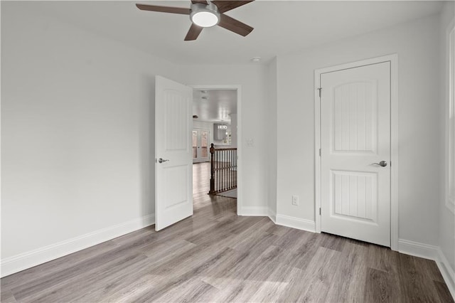 unfurnished bedroom with baseboards, a ceiling fan, and light wood-style flooring