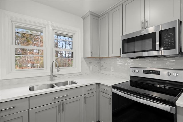 kitchen featuring a sink, gray cabinets, appliances with stainless steel finishes, and backsplash
