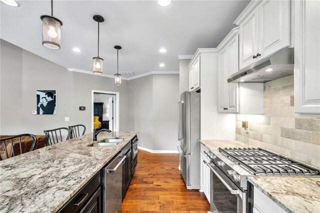 kitchen featuring sink, stainless steel appliances, pendant lighting, white cabinets, and hardwood / wood-style flooring