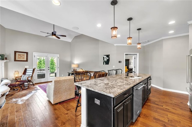 kitchen featuring a kitchen bar, sink, decorative light fixtures, a center island with sink, and dark hardwood / wood-style floors