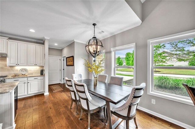 dining room featuring a chandelier, hardwood / wood-style flooring, and crown molding