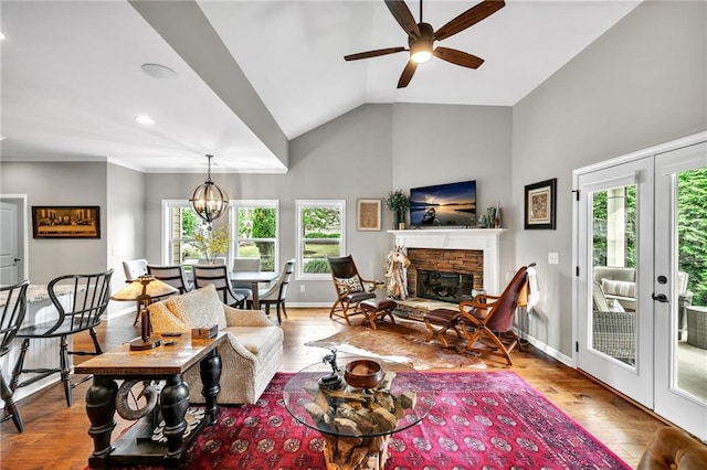 living room featuring ceiling fan with notable chandelier, light hardwood / wood-style flooring, a wealth of natural light, and vaulted ceiling