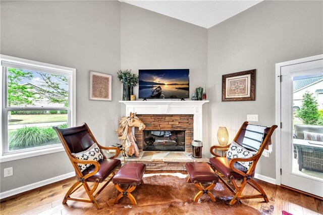 sitting room with hardwood / wood-style flooring and a stone fireplace