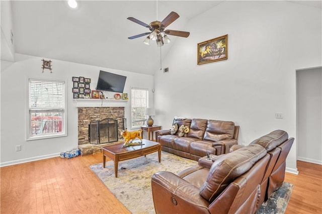 living room featuring visible vents, a ceiling fan, a stone fireplace, wood finished floors, and high vaulted ceiling