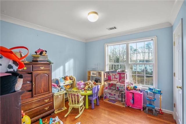 recreation room with ornamental molding, a wealth of natural light, light wood-type flooring, and visible vents