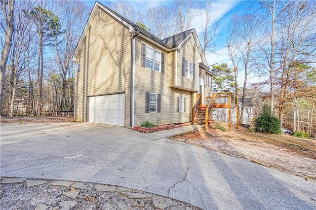 view of side of property featuring a garage, concrete driveway, and stairs