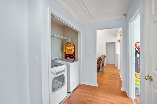 laundry room featuring light wood finished floors, attic access, separate washer and dryer, laundry area, and baseboards