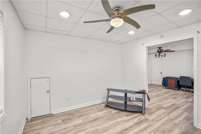 interior space featuring light wood-style flooring, baseboards, and a drop ceiling