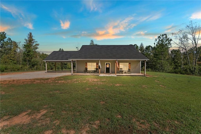 back house at dusk with a yard, a carport, and a porch