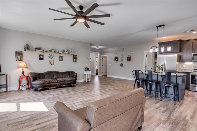 living room with ceiling fan and light wood-type flooring