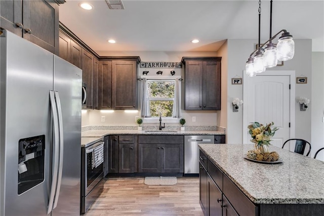 kitchen featuring a kitchen island, pendant lighting, sink, dark brown cabinetry, and stainless steel appliances