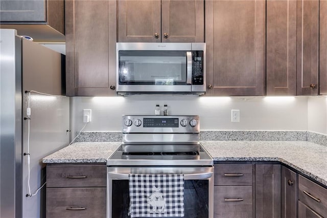 kitchen with appliances with stainless steel finishes, dark brown cabinets, and light stone counters