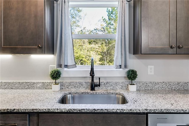 room details featuring light stone counters, sink, and dark brown cabinets