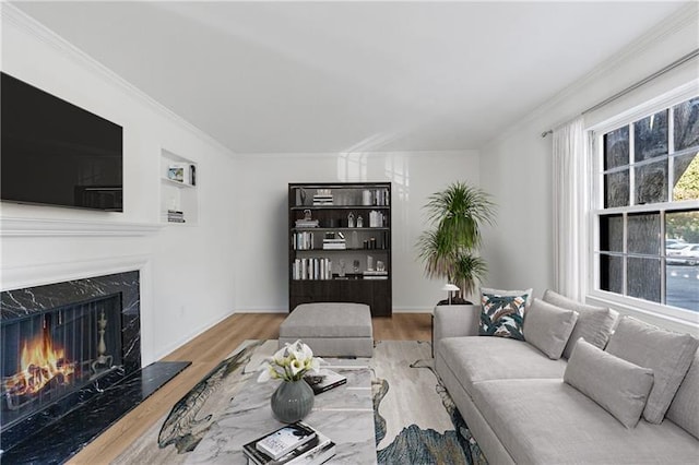 living room featuring ornamental molding, a fireplace, baseboards, and wood finished floors