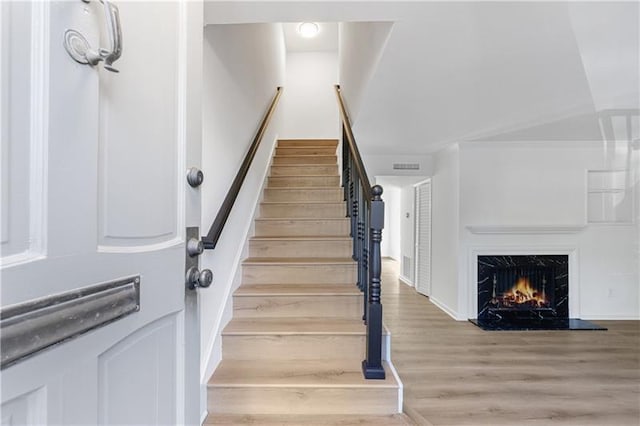 stairway featuring a fireplace, wood finished floors, and visible vents