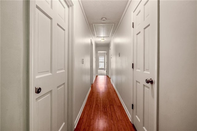 corridor with ornamental molding, hardwood / wood-style floors, and a textured ceiling