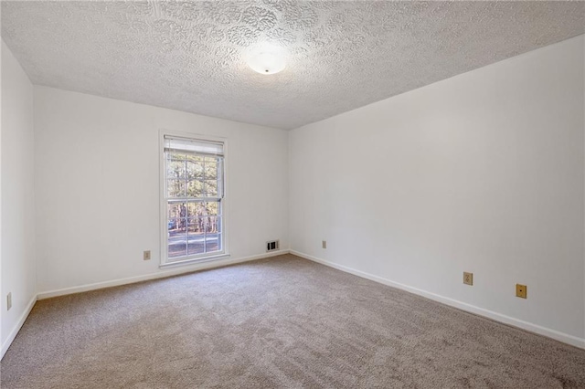 spare room with a textured ceiling and carpet flooring