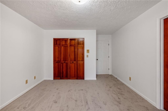 unfurnished bedroom featuring light carpet, a closet, and a textured ceiling