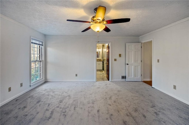 unfurnished room with ceiling fan, ornamental molding, carpet floors, and a textured ceiling