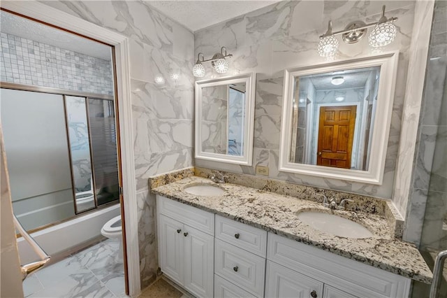 full bathroom with enclosed tub / shower combo, vanity, and toilet