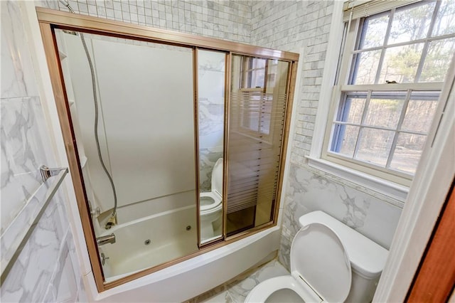 bathroom with shower / bath combination with glass door and tile walls