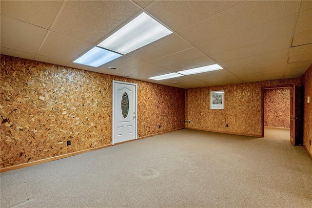 basement featuring a paneled ceiling and light colored carpet