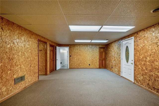 carpeted empty room featuring a drop ceiling