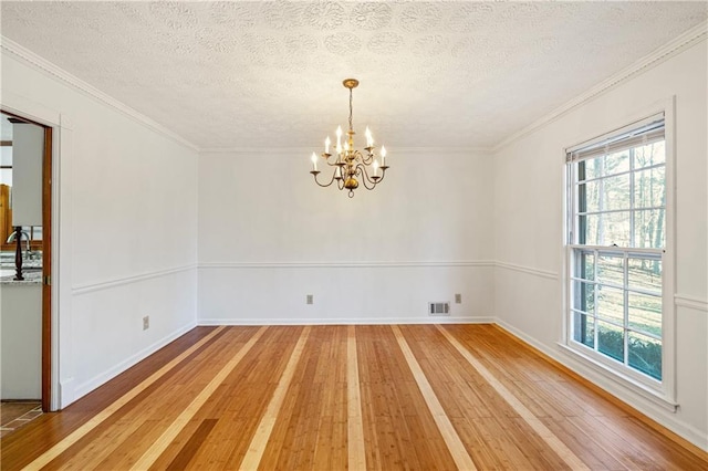 empty room with sink, crown molding, a chandelier, a textured ceiling, and hardwood / wood-style floors