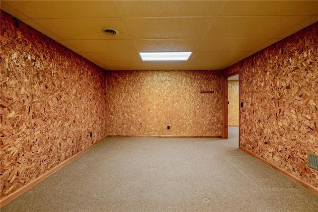 carpeted empty room featuring a paneled ceiling