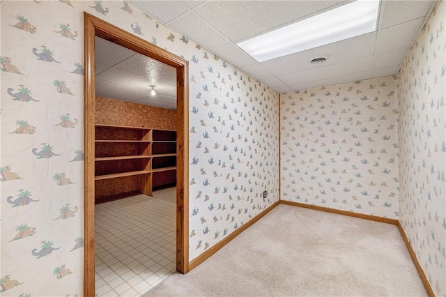 empty room featuring a paneled ceiling and light colored carpet