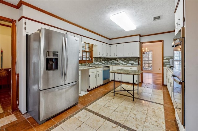 kitchen with sink, white cabinetry, appliances with stainless steel finishes, tile patterned flooring, and backsplash