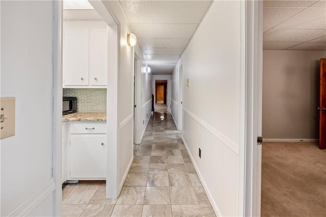 hall with light carpet and a drop ceiling