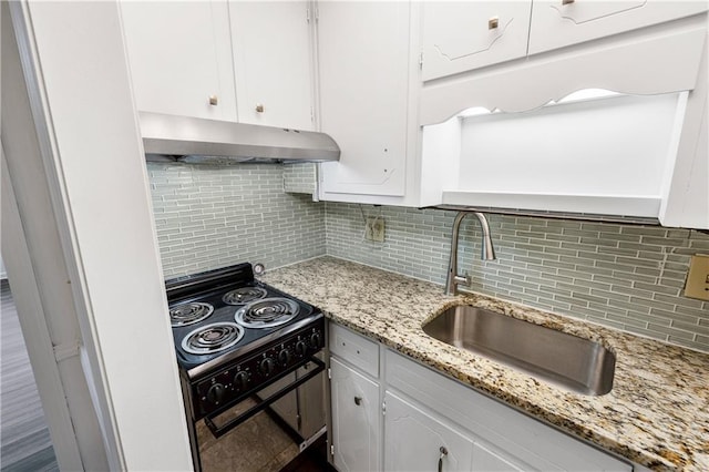 kitchen with tasteful backsplash, sink, white cabinets, and black range oven