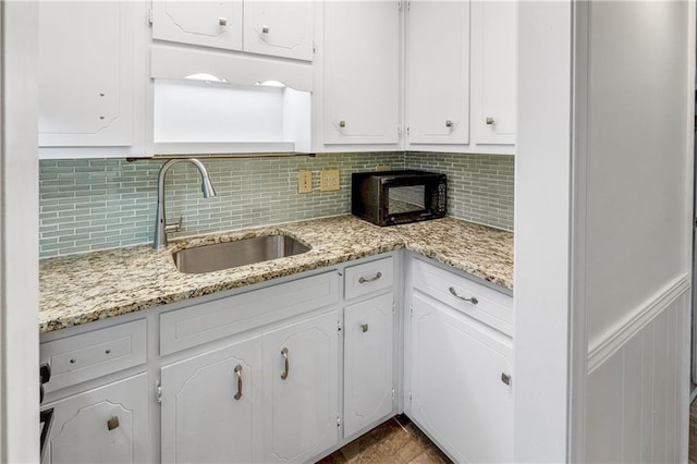 kitchen featuring white cabinetry, light stone counters, sink, and decorative backsplash