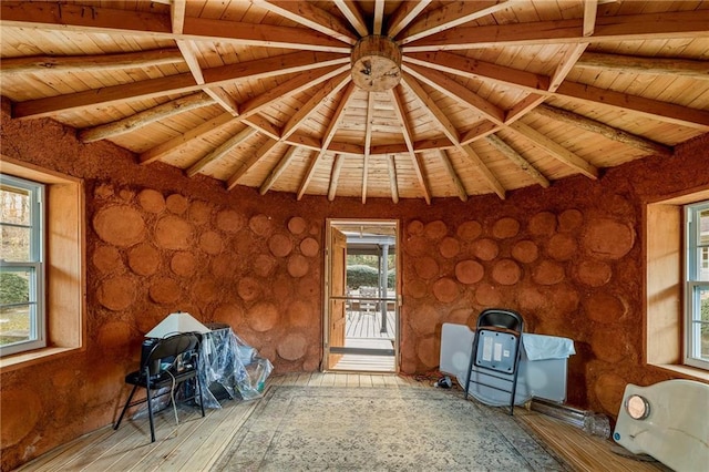 interior space with wood ceiling, lofted ceiling with beams, and a wood stove