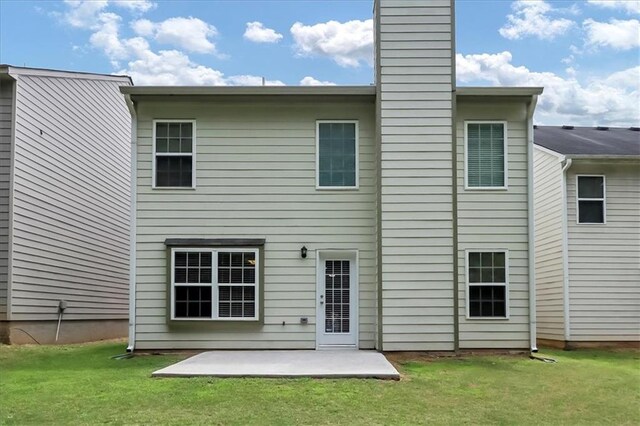 back of property featuring a yard, a patio, and a chimney