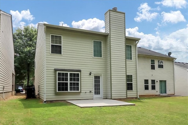 back of house with a patio, a lawn, and a chimney