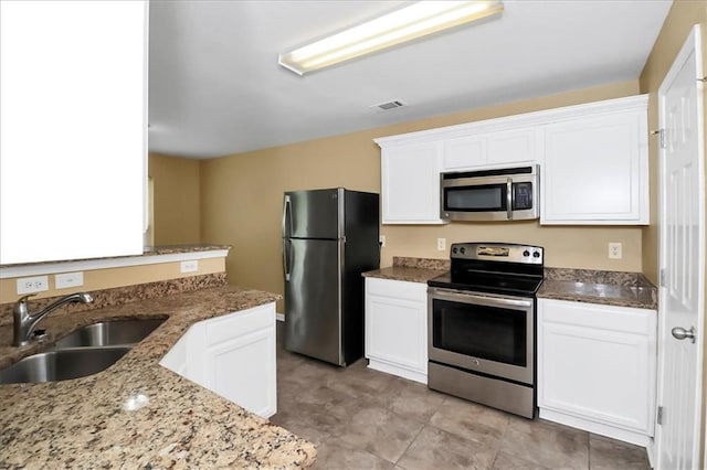 kitchen featuring visible vents, a sink, light stone counters, white cabinetry, and stainless steel appliances