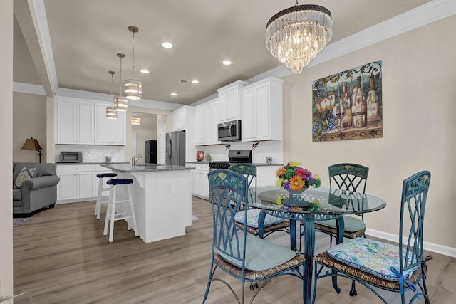 dining space with a chandelier, crown molding, recessed lighting, light wood-style flooring, and baseboards